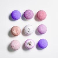 Flat lay composition with bath bomb pink, violet, purple colored on white paper background. Bathing balls with essential oils for relaxation and aromatherapy. Body care natural products photo