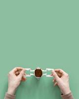 Woman hands hold opened drip coffee bag with ground coffee for brewing in cup, pack with paper bag drip coffee filter, mint color background, top view, minimal flat lay with copy space photo