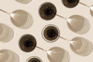Champagne glasses from gray glass on beige background as creative geometric pattern, with beautiful shadows and caustics from sun. Summer light drinks. Wine glass, top view vintage glassware photo