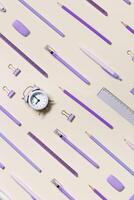 Office supplies violet color, pencils, pens, paper clips, erasers as graphic pattern. School stationery flat lay on table. Back to school concept, beige background. Top view, diagonal photo