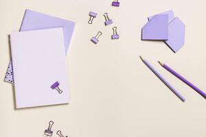 School stationery flat lay very peri trend colored. Back to school concept, notebook, note, pen, paperclips on pastel beige background. Office equipment, view from above, minimal photo