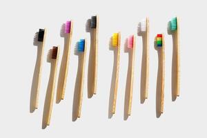 set of Eco friendly Bamboo toothbrushes with colored bristles at sunlight with dark shadows on white background. Sustainable living concepts, minimal style aesthetic photo, top view wood oral brushes photo
