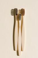 Eco-friendly Bamboo toothbrushes with white bristles at sunlight with dark shadows on beige background. Sustainable living concepts, minimal style aesthetic photo, top view set wooden brushes photo