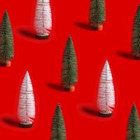 Pattern with shining Christmas tree white and green color on red background. Minimal New Year layout with mini festive fir, xmas decor ornament, winter holiday concepts photo