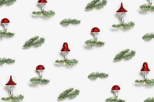 Christmas pattern with botanical ornaments fly agaric mushrooms with red cap and white dots, on natural green christmas fir tree branches on white background. Holiday winter decor photo