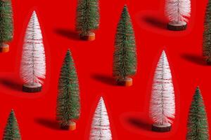 Pattern of shining Christmas tree white and green color on red background. Minimal New Year layout with mini festive fir, xmas decor ornament, winter holiday concept photo