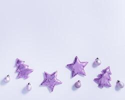 Christmas background with shining lavender color soft toys with sequins, shape Christmas fir tree and star, monochrome image. New Year holiday greeting card, invitation, trend color photo