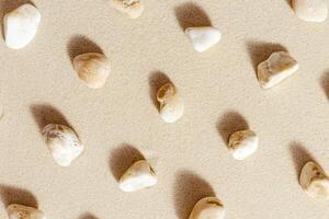 Pattern with pebble sea stones on fine sand. Natural stone neutral beige yellow color, monochrome tones. Summer minimal design background photo