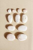 Pattern with white pebble sea stones on fine sand. Square composition from natural stone neutral beige color, monochrome tones. Spa minimal background photo
