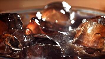 A glass of cola with ice. Splashes on the surface. Filmed on a high-speed camera at 1000 fps. High quality FullHD footage video