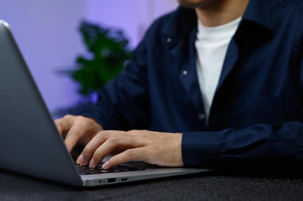 Person Working at Computer with Modern Laptop in Indoor Setting