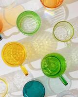 Colored shiny drink Glasses still life with shadow and sunlight reflections on white, minimal aesthetic top view summer photo, refraction at glass cups with sun flare, creative contemporary pattern photo
