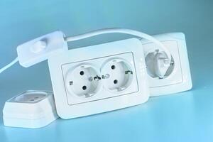 Three electrical sockets for connecting devices and a switch on blue photo