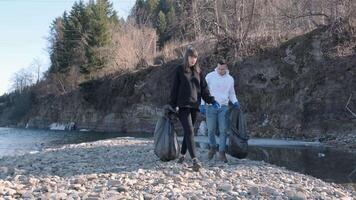Person Carrying Trash Bag While Walking Near Stream video