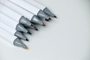 Open markers arranged neatly on white surface photo