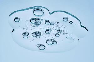 A beautiful swatch of hyaluronic serum with bubbles on a blue background. View from below. photo