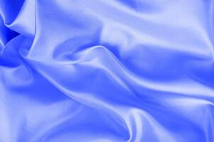Top view of light blue color silk in soft, smooth waves with a glossy finish. Suitable for design and wallpaper background photo