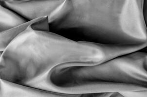 Close up of luxurious black silk fabric with elegant folds and smooth, glossy surface texture. photo
