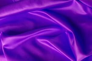 Top view of shiny maroon satin cloth with radiant surface highlights and fine woven texture in natural folds photo