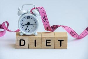 Diet text on wooden cube with alarm clock and measuring tape background photo