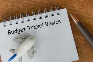Flat lay of Budget Travel Basics notepad and toy airplane. Travel budgeting with conservation in mind photo