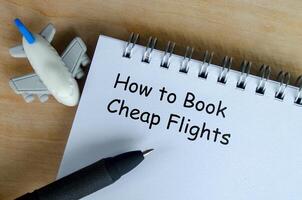 How to book a cheap flights text on white notepad with airplane and black pen background photo