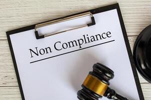 Top view of Non Compliance text on clipboard with gavel on top. Compliance concept. photo