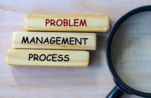 Top view of Problem Management Process text on wooden blocks with magnifying glass as background. Root cause analysis concept photo