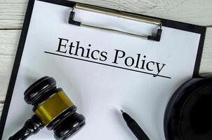 Top view of Ethics Policy text on white paper clipboard with gavel photo