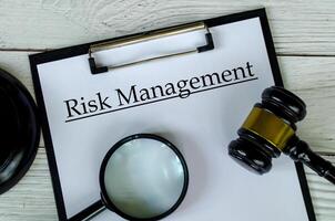 Top view of Risk management text on white paper clipboard with gavel and magnifying glass photo