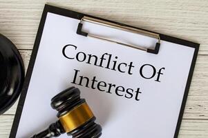 Top view of Conflict Of Interest text on clipboard with gavel on top. Conflict of interest concept photo