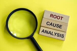 Root Cause Analysis text on wooden blocks with magnifying glass as background. Root cause analysis concept photo