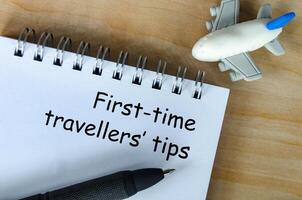 Top view of First Time Traveller tips text on white notepad. Getaway concept. photo