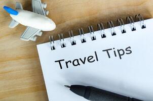 Top view of Travel Tips text on white notepad. Getaway concept. photo