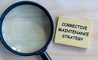 Top view of Corrective Maintenance Strategy text on wooden blocks with magnifying glass. photo