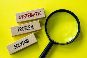 Top view of Systematic Problem Solving text on wooden blocks with magnifying glass. photo
