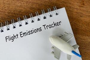 Flight Emissions tracker text on white notepad with small airplane background. Environmental awareness. photo