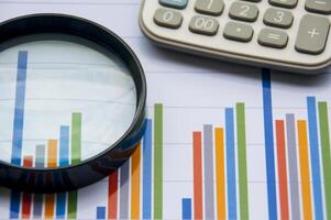 Graph analysis with calculator and magnifying glass. Financial analysis concept photo