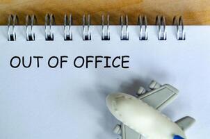 Out Of Off text on white notepad with small airplane. Out of office concept and getaway. photo