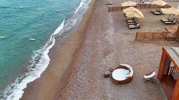 Drone view of gentle waves, footprints in the sand and wooden cabana on beach video