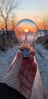 Sunset Reflected Within a Lightbulb Held in a Hand's Grip photo