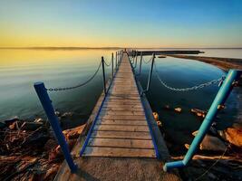 Serene Sunset Over Wooden Lake Pier with Chain Railings photo