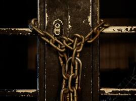 Weathered Door Secured by Heavy Chain and Lock, Dark and Moody photo