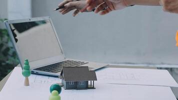 A man is pointing at a laptop with a model of a house on it video