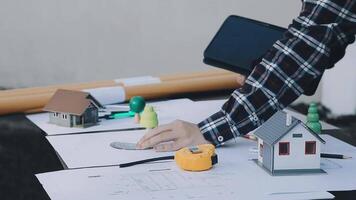 A person is working on a project with a tablet and a house model video