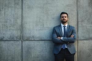 a man in a suit and tie standing against a wall photo