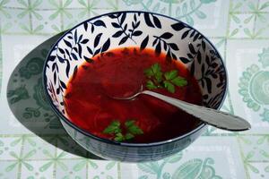 Discover the rich flavors of borscht, a traditional Ukrainian beetroot soup served in an ornate bowl with a touch of fresh herbs for a delightful touch photo