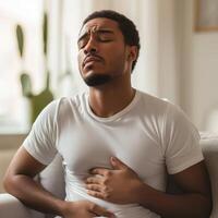 Young man suffering from stomach or heart pain at home photo