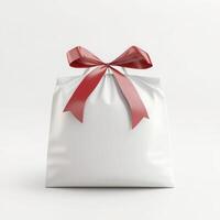 Glossy white gift bag tied with red ribbon bow standing on white background representing celebration, holidays, birthdays, and special occasions photo