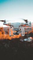White drone flying and recording a landscape at sunset photo